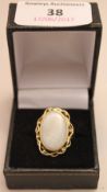 A 9 ct gold opal set ring The large white cabochon opal set in scrolling framework. 2.5 cm high.