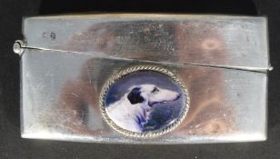 A silver card case depicting a dog