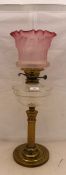 A Victorian oil lamp with cranberry glass shade