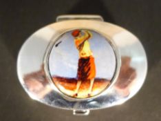 A silver pill box depicting a golfer