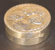 A silver pill box depicting cherubs