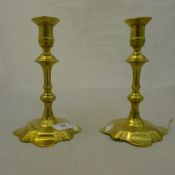 A pair of early 18th century petal base brass candlesticks