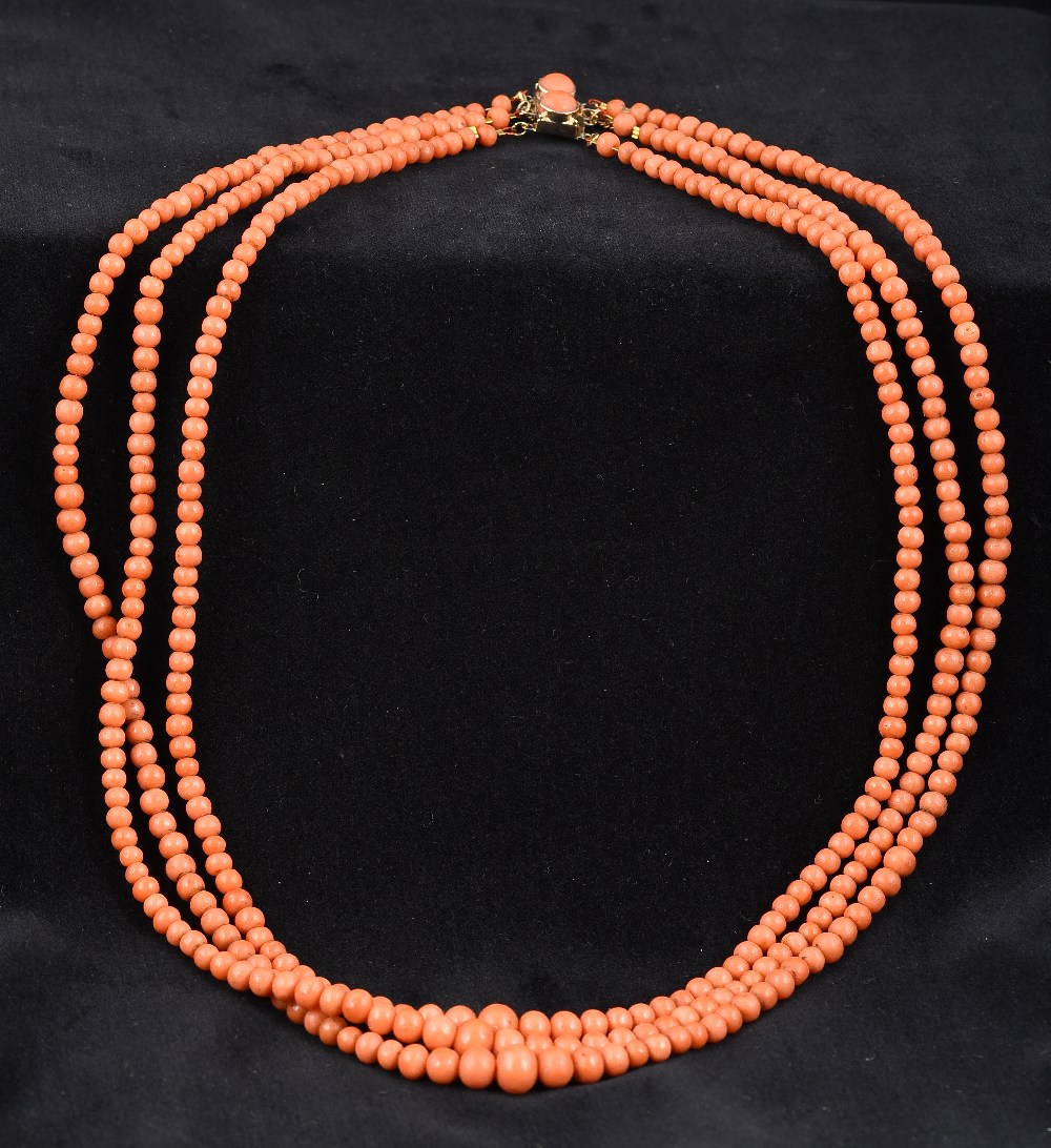 A three strand coral bead necklace The clasp set with two coral cabochons.