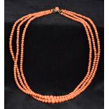 A three strand coral bead necklace The clasp set with two coral cabochons.