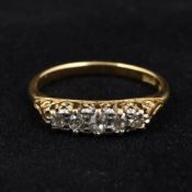An 18 ct gold diamond set five stone ring Each claw set stone above scrolling pierced shoulders.