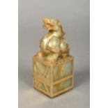 A Chinese carved russet jade and gilt decorated seal Surmounted with a mythical beast,