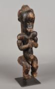 An African tribal figure Formed as a seated male holding a cup, mounted on a later display stand.