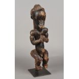 An African tribal figure Formed as a seated male holding a cup, mounted on a later display stand.