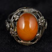 An Art Nouveau pierced silver ring The pierced floral bands centred with an amber cabochon.