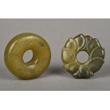 Two Chinese carved jade roundels Each centrally pierced. The largest 5.25 cm diameter.