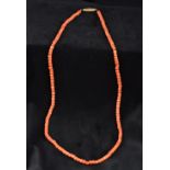 A single strand coral bead necklace Set with an enamel decorated unmarked yellow metal clasp.