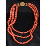 A large three strand coral bead necklace Set with a cabochon mounted pierced gold clasp.