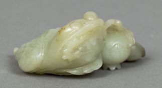 A Chinese carved celadon and russet jade figure of a toad Naturalistically modelled with a fruiting
