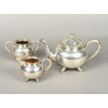 A Chinese Export silver three piece tea set by Tsun Tsun The teapot with faux bamboo handle and