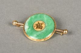 A Chinese gold mounted apple green jade brooch Of circular form, centred with calligraphy.