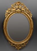 A large Victorian gilt wall glass The bevelled oval mirror plate surmounted with a floral filled