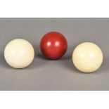 Two turned ivory billiards balls, together with a further red stained billiards ball 5 cm diameter.