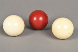 Two turned ivory billiards balls, together with a further red stained billiards ball 5 cm diameter.
