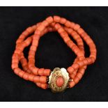 A three strand coral bead bracelet Set with a coral cabochon mounted clasp.