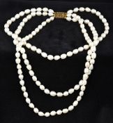 A three strand baroque pearl necklace Mounted with a 15 ct gold clasp. 43 cm long.