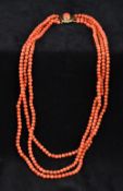 A three strand coral bead necklace Set with a cabochon coral mounted unmarked clasp. 46 cm long.