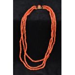 A three strand coral bead necklace Set with a cabochon coral mounted unmarked clasp. 46 cm long.