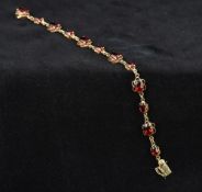 A 9 ct gold garnet set bracelet Each stone in a pierced scrolling setting. 17.5 cm long.