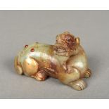 A Chinese carved and russet jade gilt decorated and gem set temple lion Modelled recumbent.