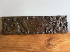 A 17th century carved oak panel Worked with a pair of cherubs flanking an heraldic motif worked