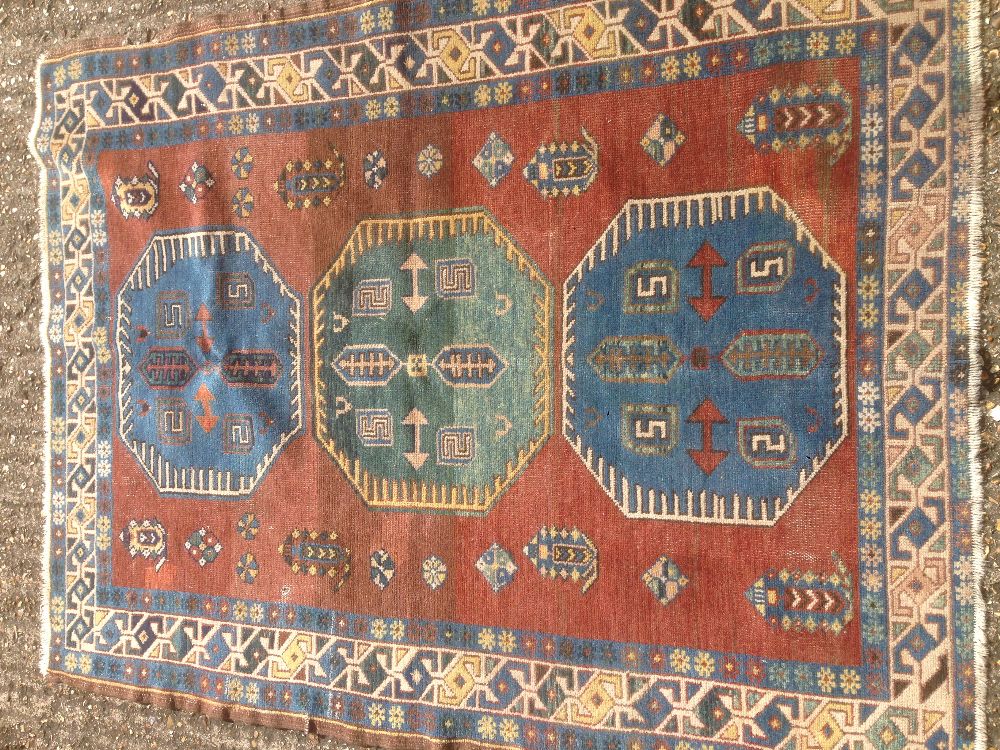 A Caucasian wool rug The tan field enclosing three medallions within rosettes and boteh,
