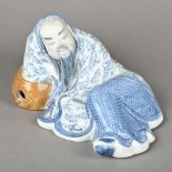 A Chinese blue and white porcelain figure Modelled as a reclining sage. 24 cm long.