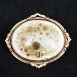 An early 19th century unmarked gold memorium brooch Of scrolling oval form centred with a fine