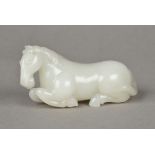 A Chinese carved celadon jade stallion Modelled recumbent. 9 cm long.