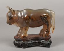 A Chinese carved agate group Worked as a cow or bull, standing on a carved and pierced wood base.