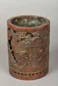 A Chinese cast bronze brush pot Decorated in relief with figures playing Go beside a pagoda in a