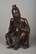 A Chinese carved hardwood figure of a sage Worked seated holding a flower. 18.5 cm high.