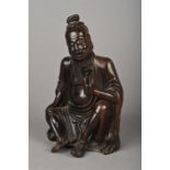 A Chinese carved hardwood figure of a sage Worked seated holding a flower. 18.5 cm high.