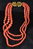 A large three strand coral bead necklace Set with an 18 ct gold filigree clasp.