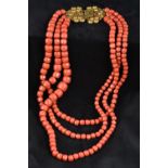 A large three strand coral bead necklace Set with an 18 ct gold filigree clasp.