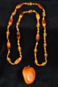 A large polished butterscotch amber pendant Together with an amber bead necklace. The former 6.