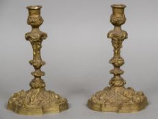 A pair of cast bronze candlesticks Worked with C-scrolls and floral sprays,