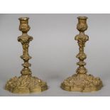 A pair of cast bronze candlesticks Worked with C-scrolls and floral sprays,