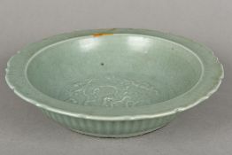 An antique Chinese celadon glazed pottery bowl With crimped edge centred with a dragon amongst