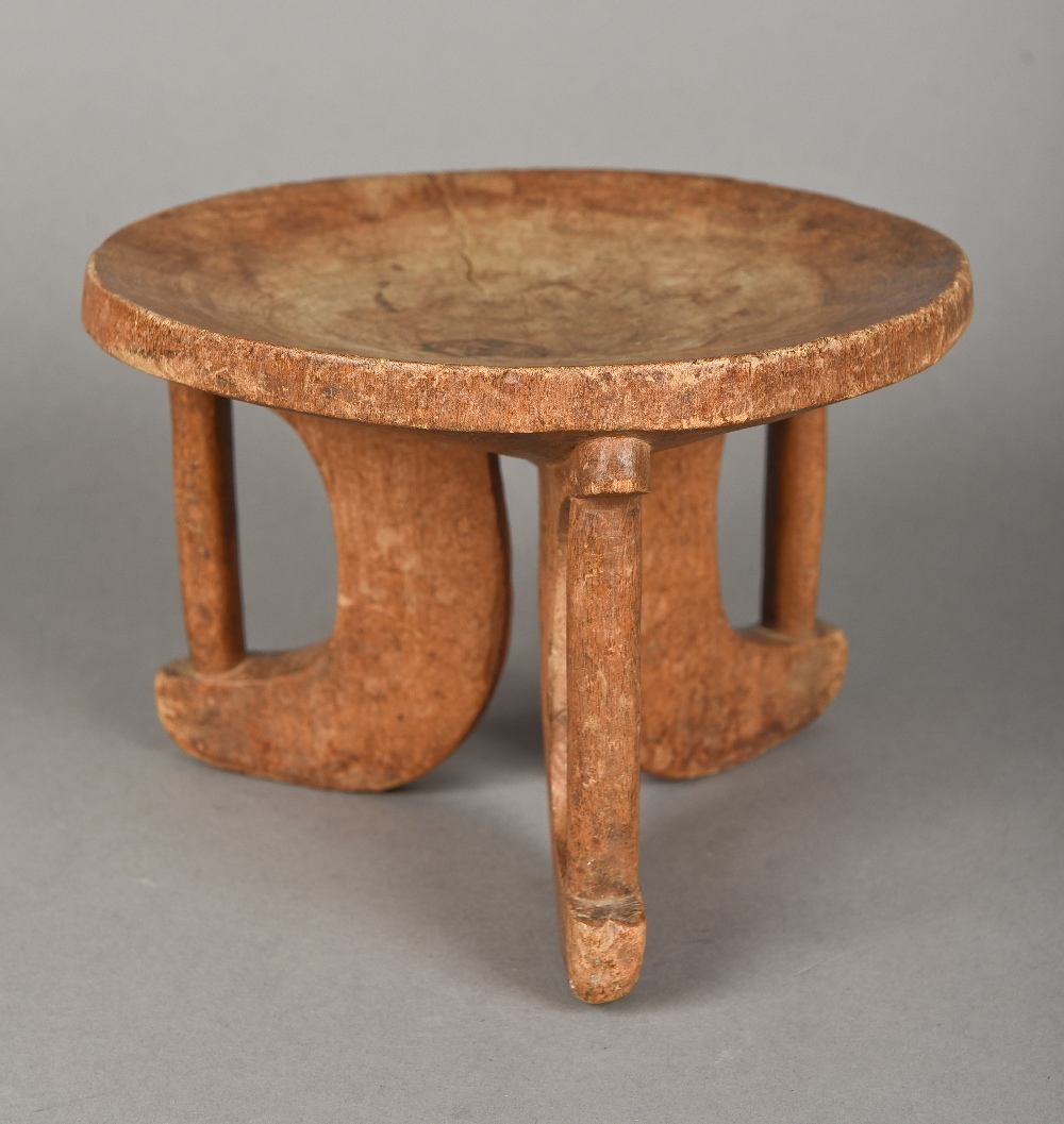 An African carved wooden tribal stool Of dished circular form with three pierced legs. 14.