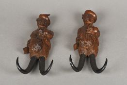 Two late 19th/early 20th century Black Forest carved coat hooks Each formed as a fox carrying a gun,