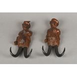 Two late 19th/early 20th century Black Forest carved coat hooks Each formed as a fox carrying a gun,