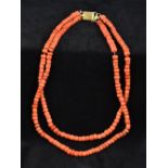 A two strand coral bead necklace Set with a plain gold clasp. Approximately 48 cm long.