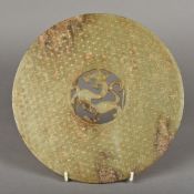 A Chinese carved green and russet jade bi disc The centre pierced and carved with a dragon.