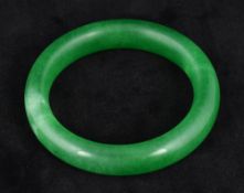 A Chinese apple green jade bangle Of plain form. 8 cm diameter.