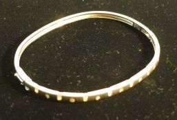 A 9 ct white gold and diamond set contemporary bangle